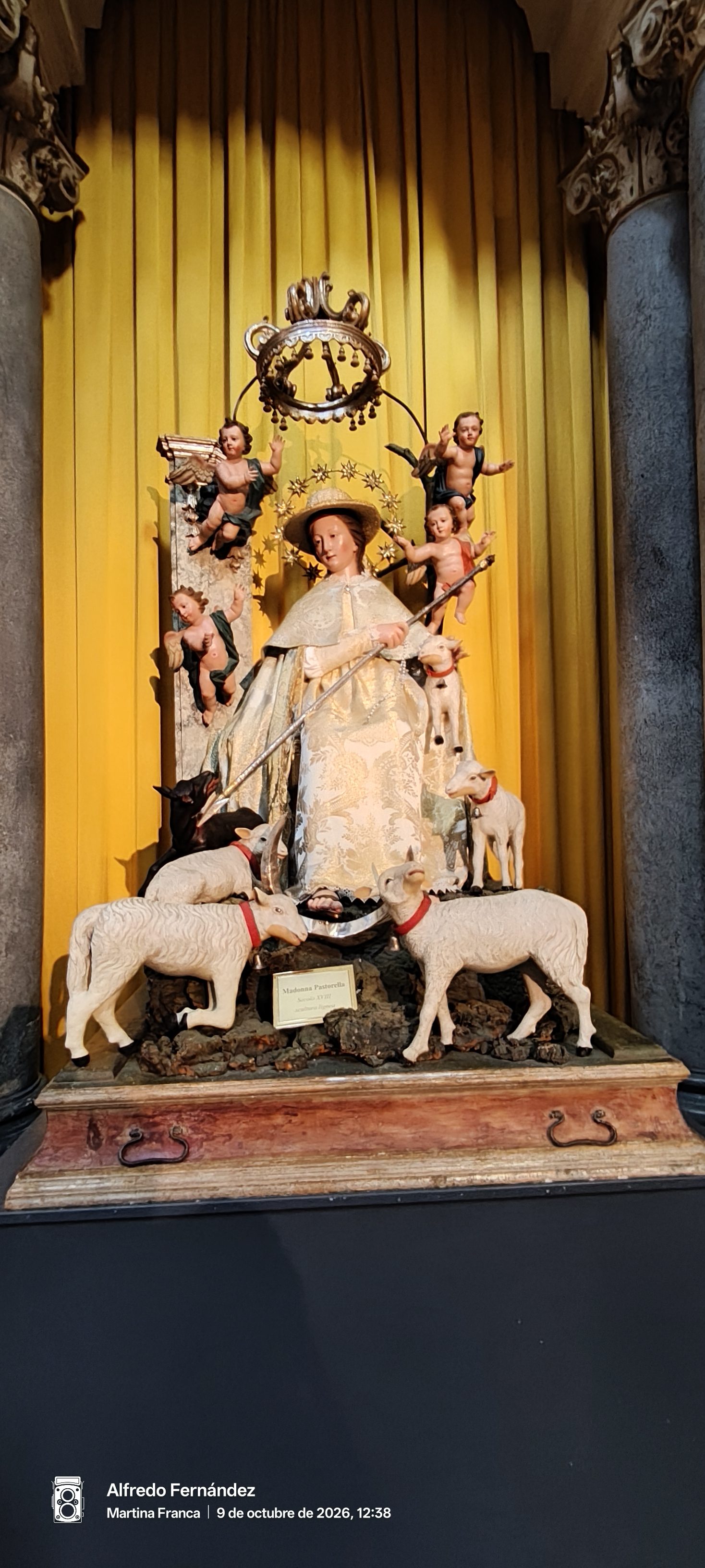 Escultura barroca de madera de la Madonna Pastorella rodeada de ovejas y querubines.
