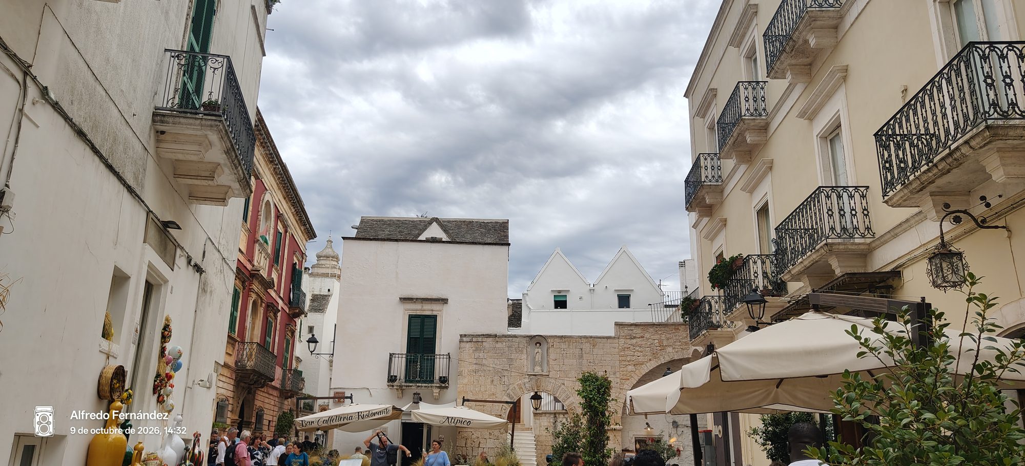 Plaza con edificios blancos y tejados puntiagudos tradicionales bajo un cielo nublado en Locorotondo.
