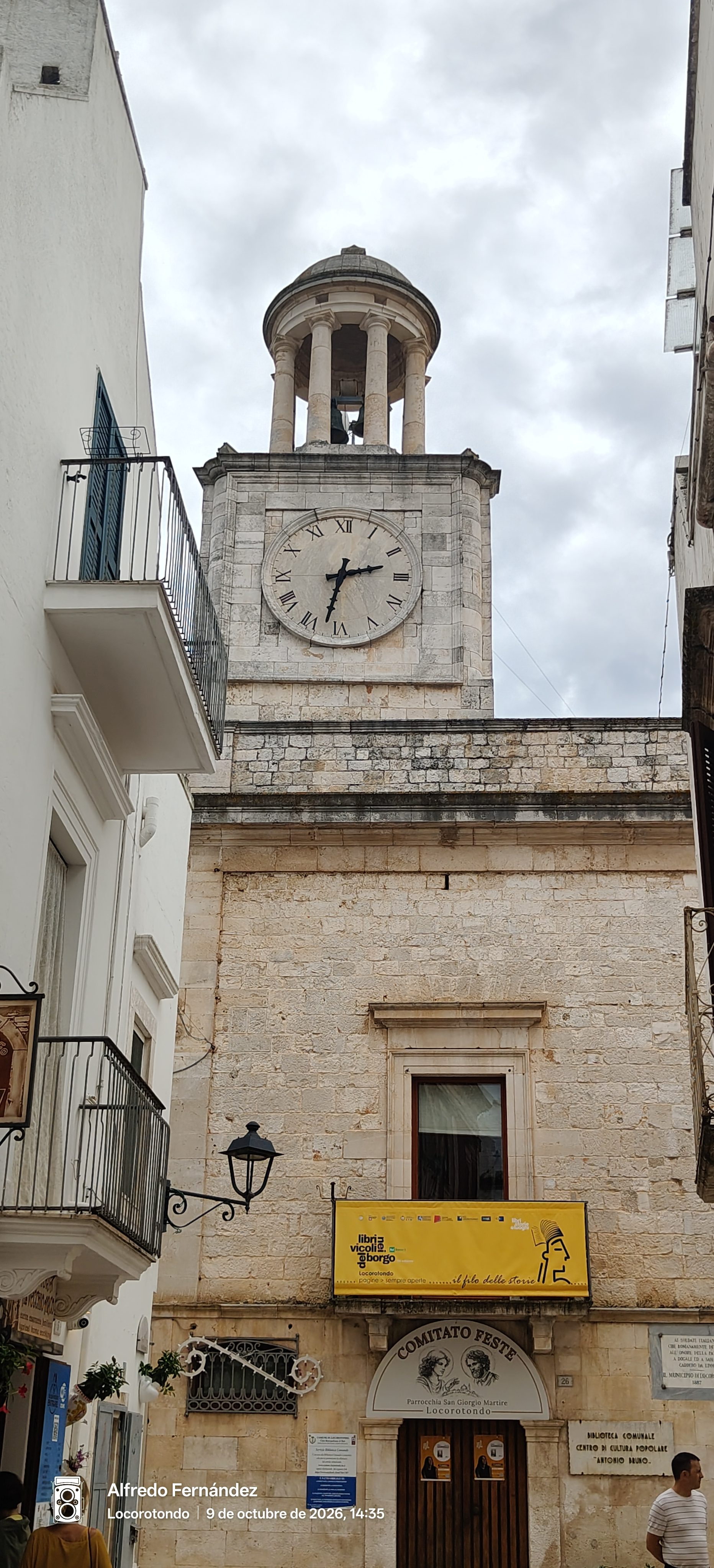 Torre del reloj de piedra y campanario en una calle de Locorotondo.