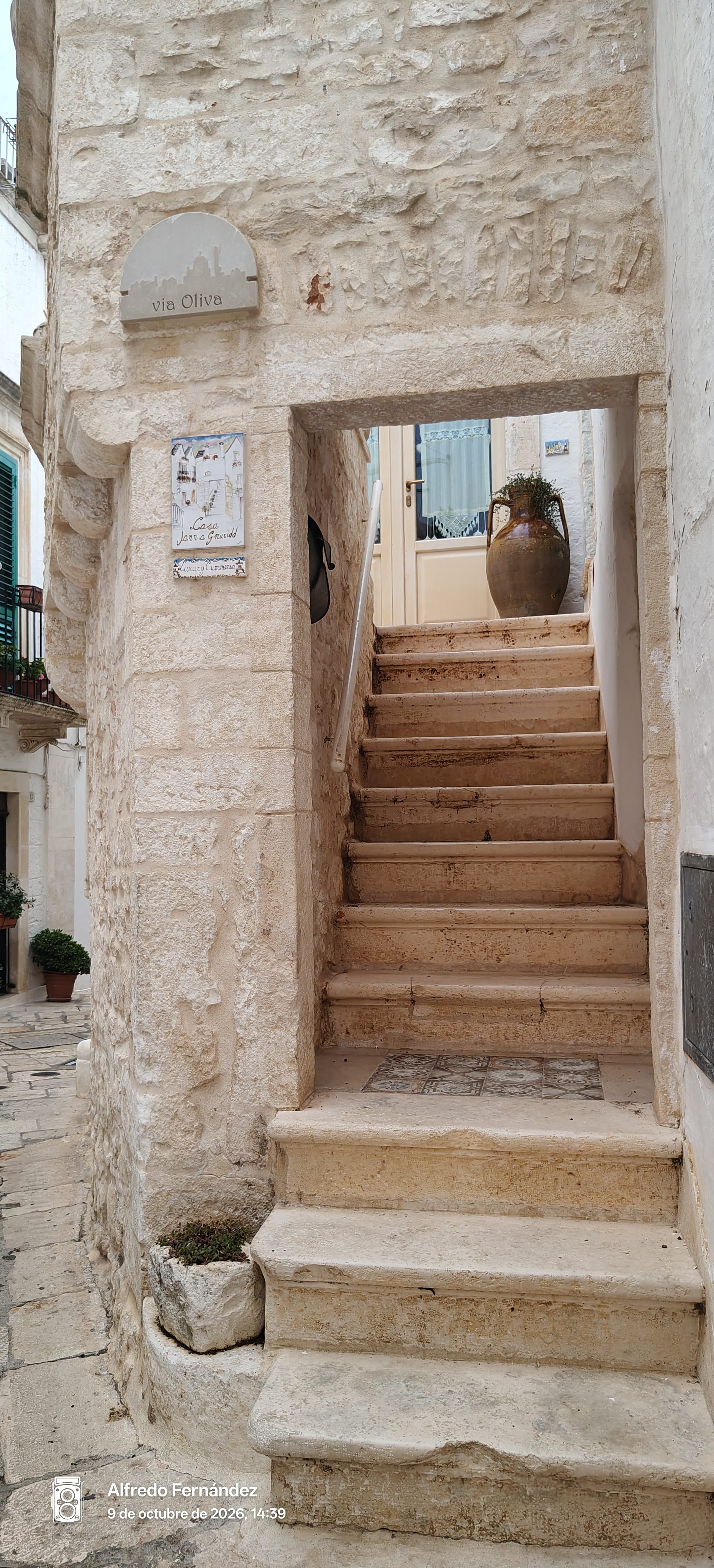 Escalera exterior de piedra caliza hacia una vivienda tradicional en una callejuela.