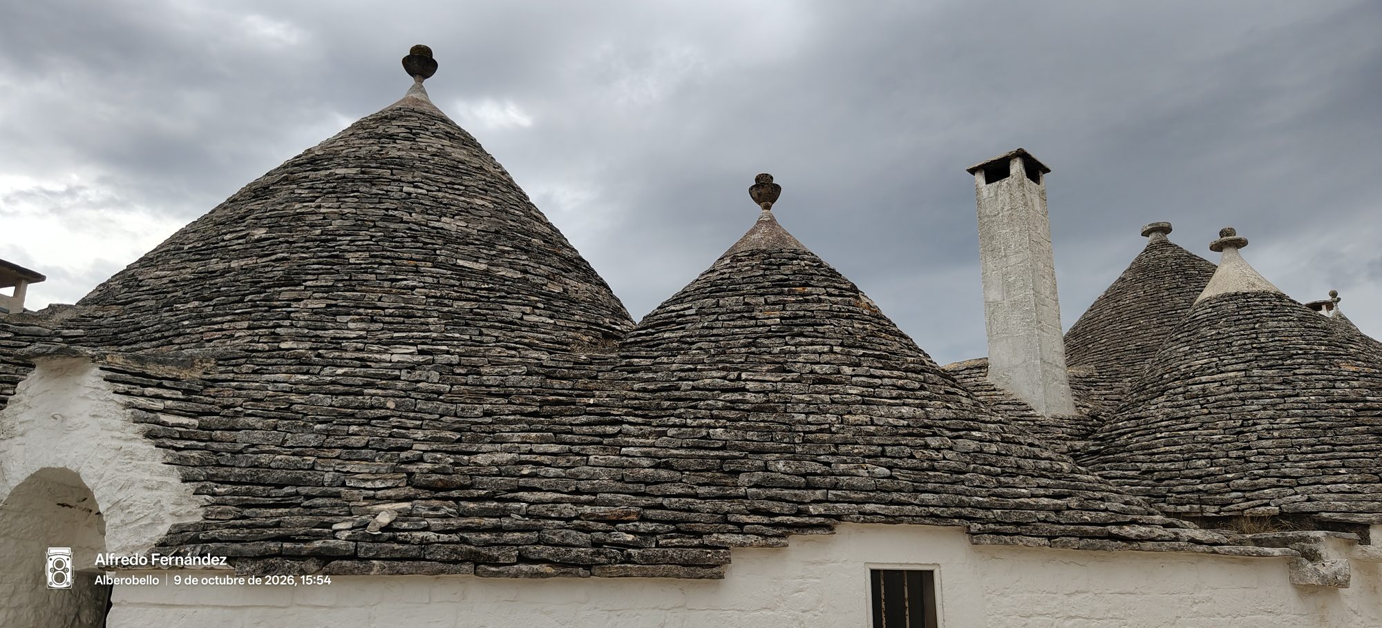 Tejados cónicos de piedra de los tradicionales trulli bajo un cielo nublado.