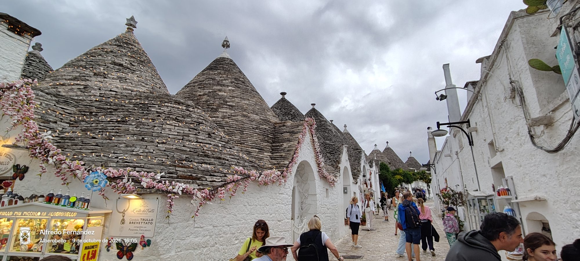 Calle empedrada flanqueada por tradicionales trulli con tejados cónicos de piedra en Alberobello.