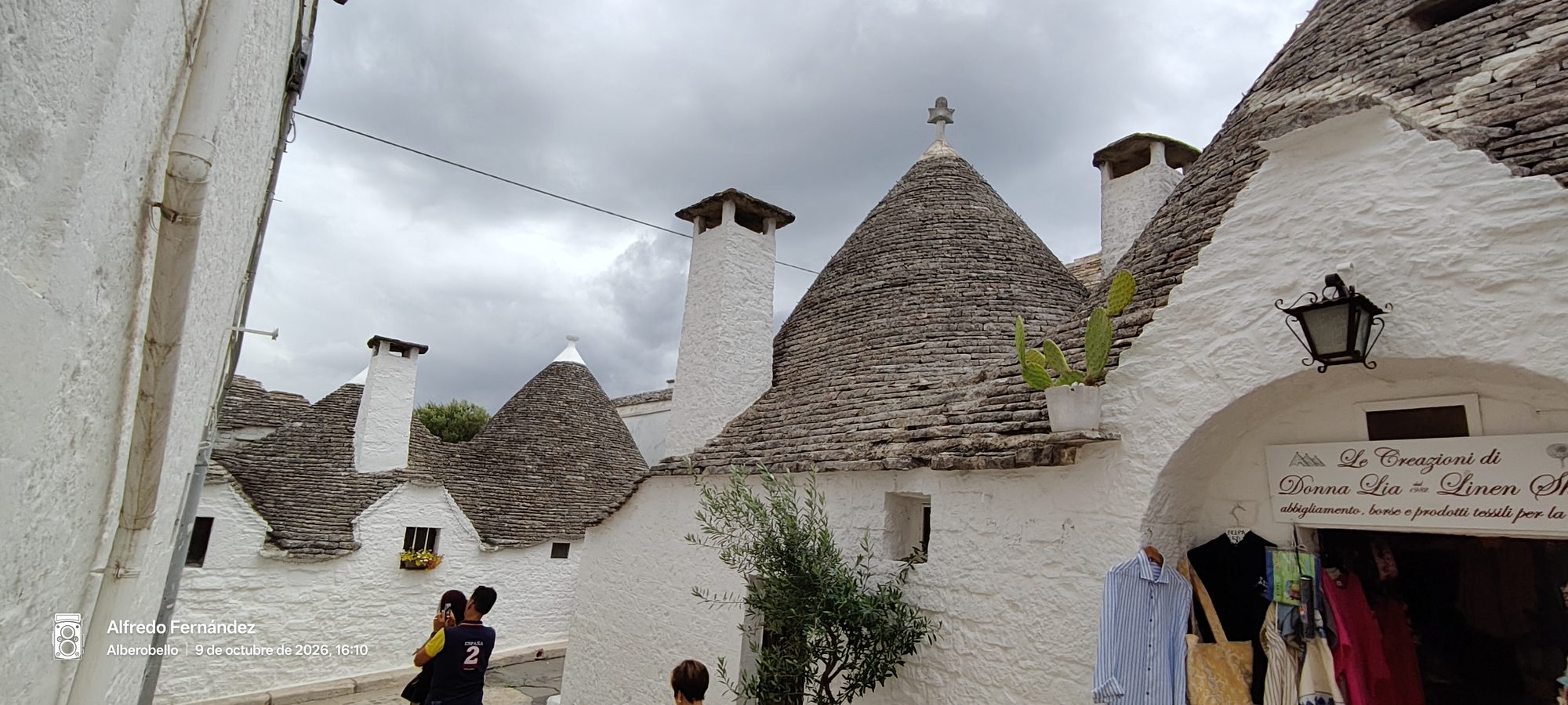 Tradicionales casas trulli con tejados cónicos de piedra y fachadas blancas bajo cielo nublado.