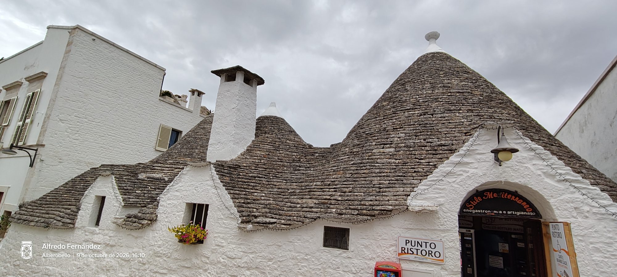 Tradicionales trulli con techos cónicos de piedra y paredes encaladas bajo cielo nublado.