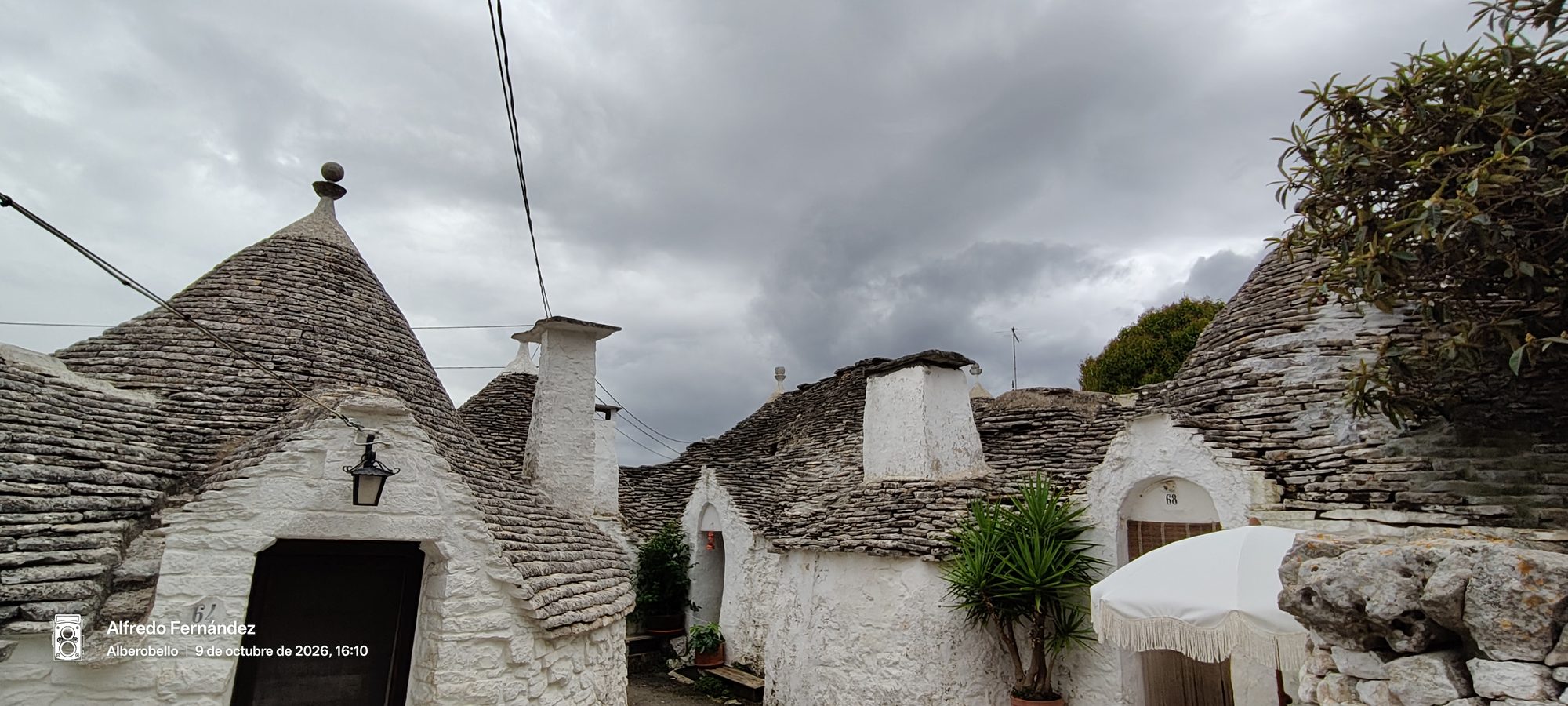 Tejados cónicos de tradicionales trulli de piedra blanca bajo un cielo nublado.