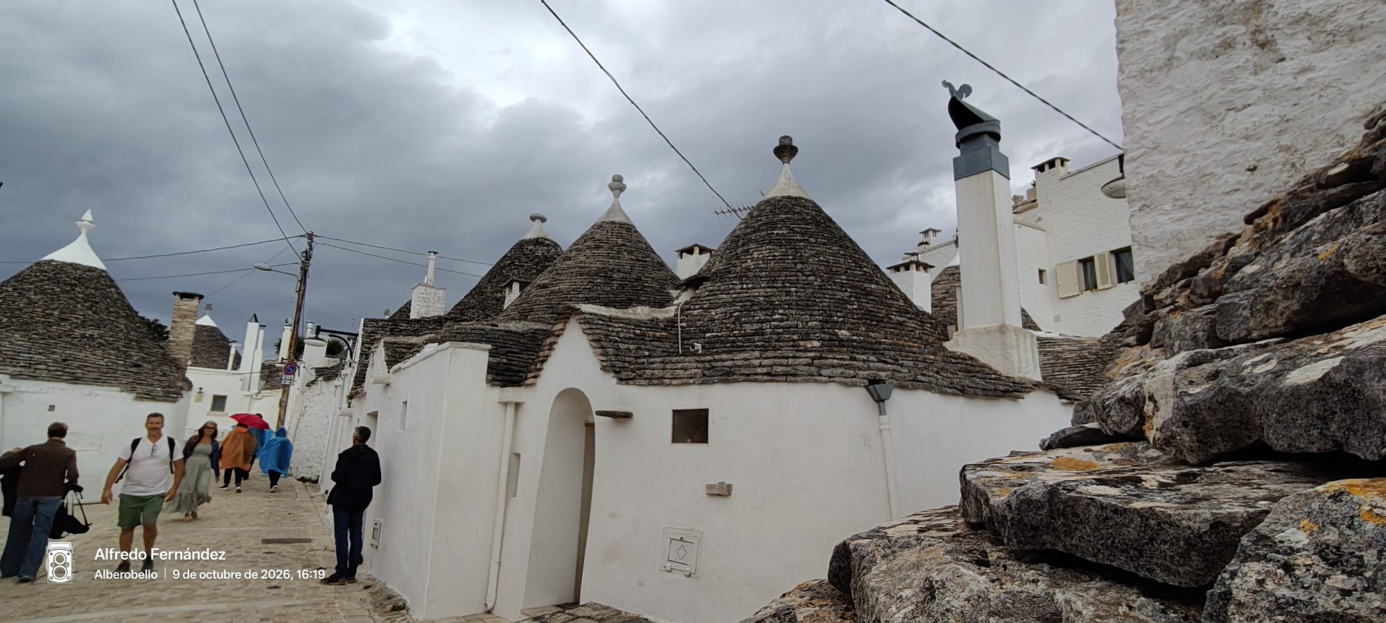 Trulli tradicionales con techos cónicos de piedra bajo un cielo nublado en Alberobello.