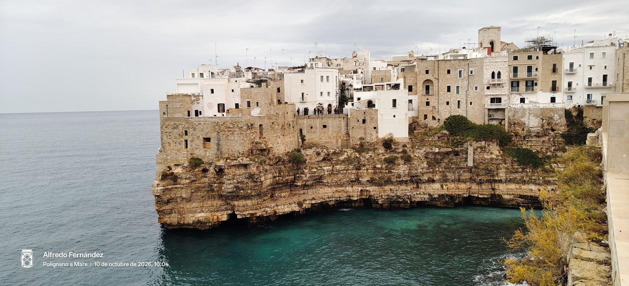 Casas blancas históricas construidas sobre los acantilados rocosos frente al mar turquesa.