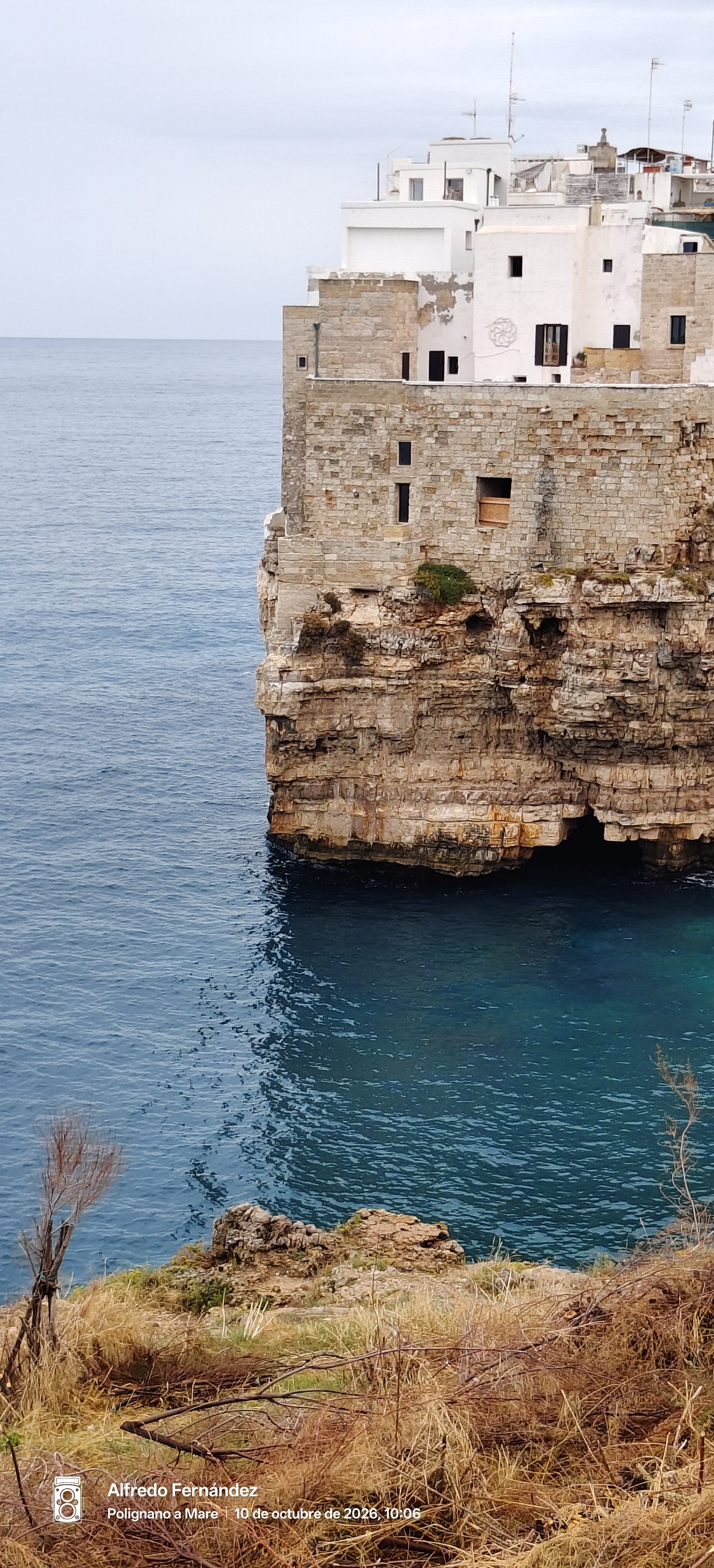 Casas de piedra construidas sobre un acantilado rocoso frente al mar azul.