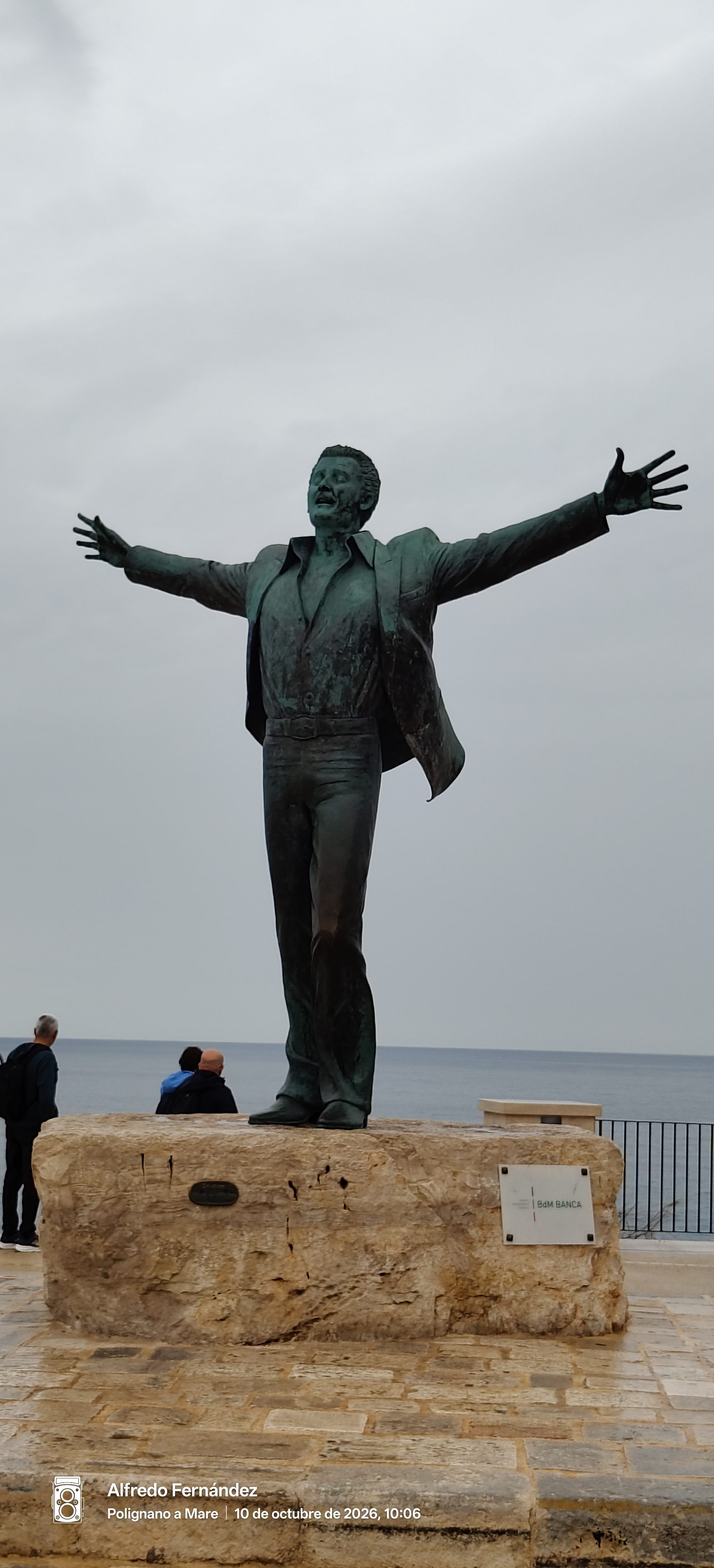 Estatua de bronce de Domenico Modugno con los brazos abiertos frente al mar.