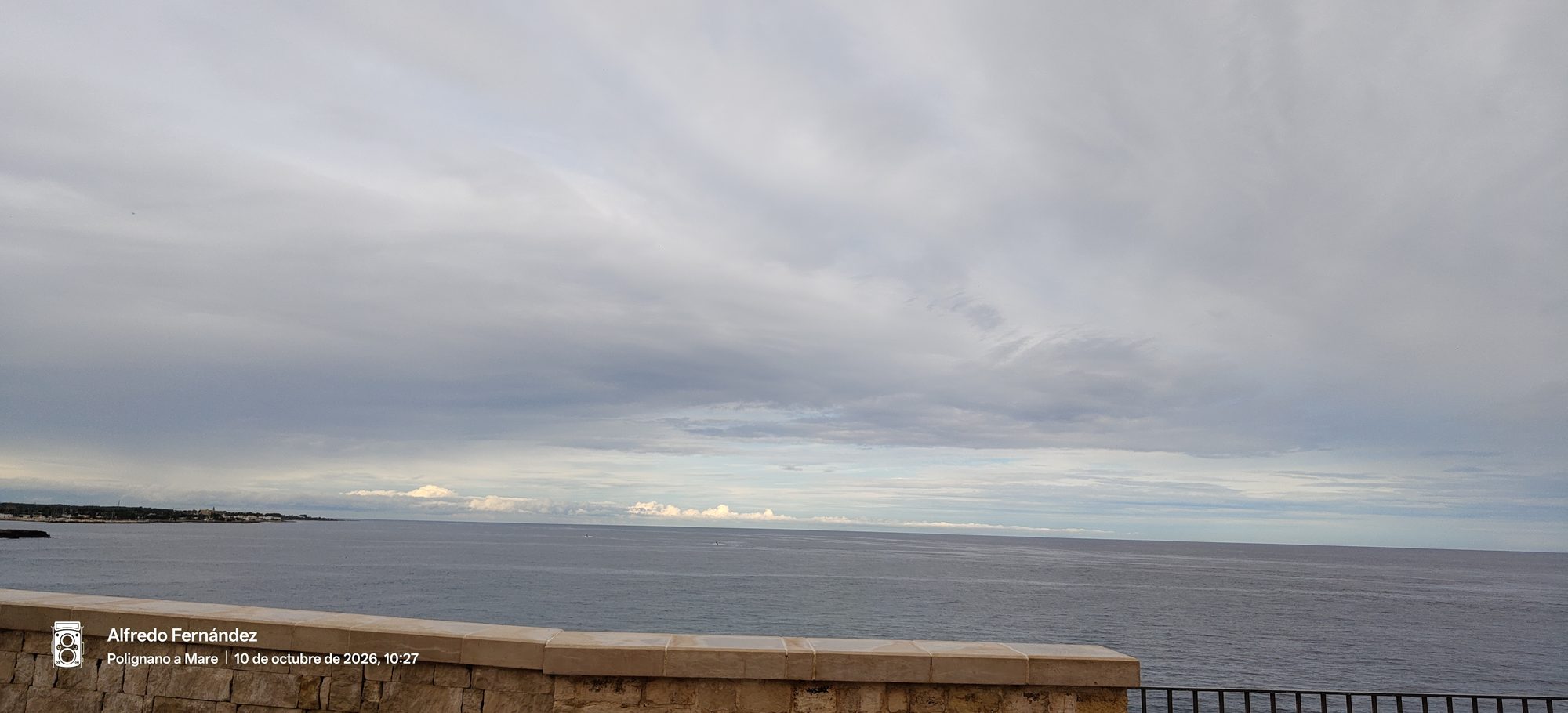 Vista del mar Adriático en calma bajo un cielo nublado desde un mirador de piedra.