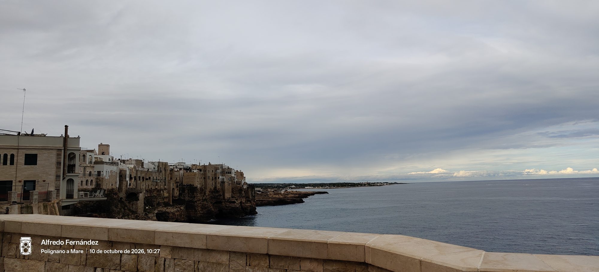 Casas históricas sobre acantilados frente al mar Adriático bajo un cielo nublado.
