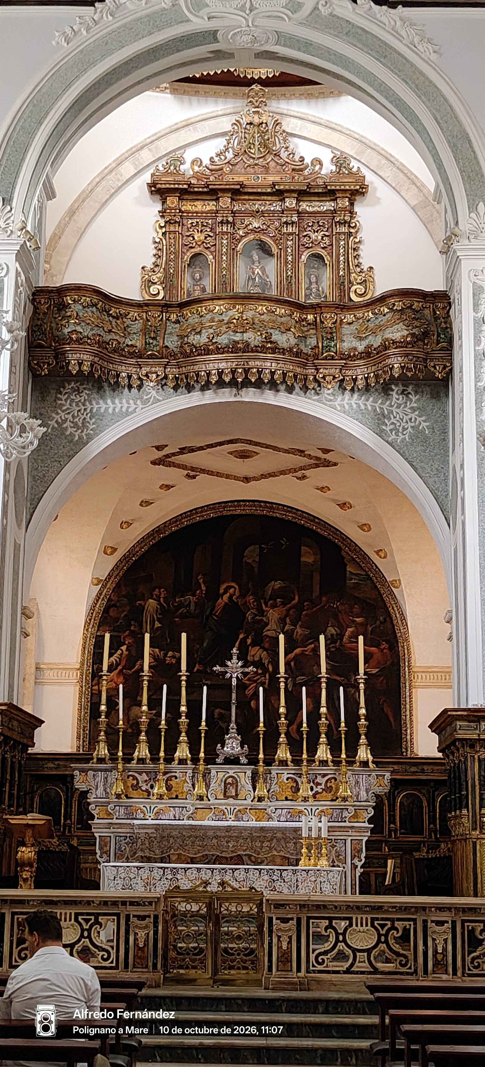 Altar mayor barroco con candelabros dorados y retablo en una iglesia histórica italiana.