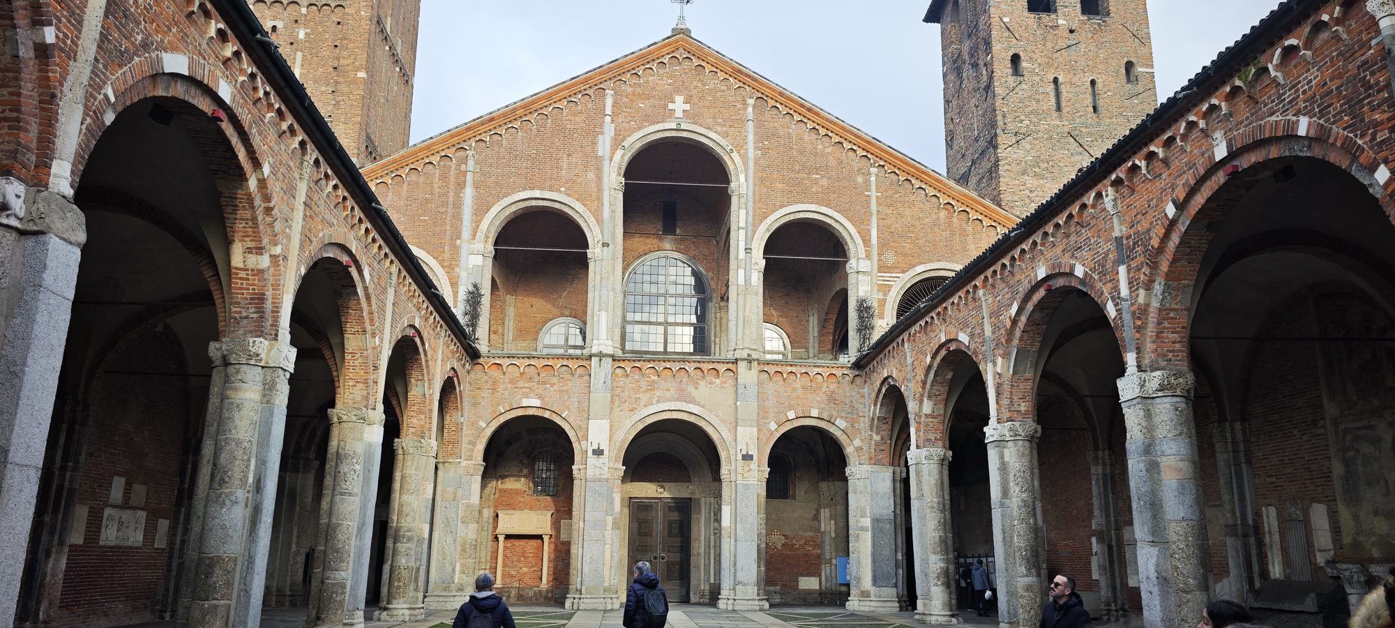 Fachada de ladrillo rojo y atrio con arcos de la Basílica de San Ambrosio.