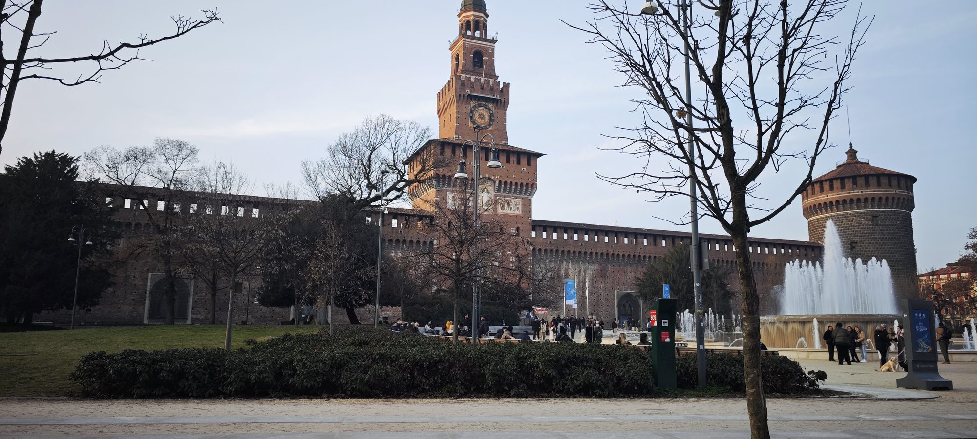 Castillo Sforzesco de Milán con su torre principal, murallas medievales y fuente frontal.