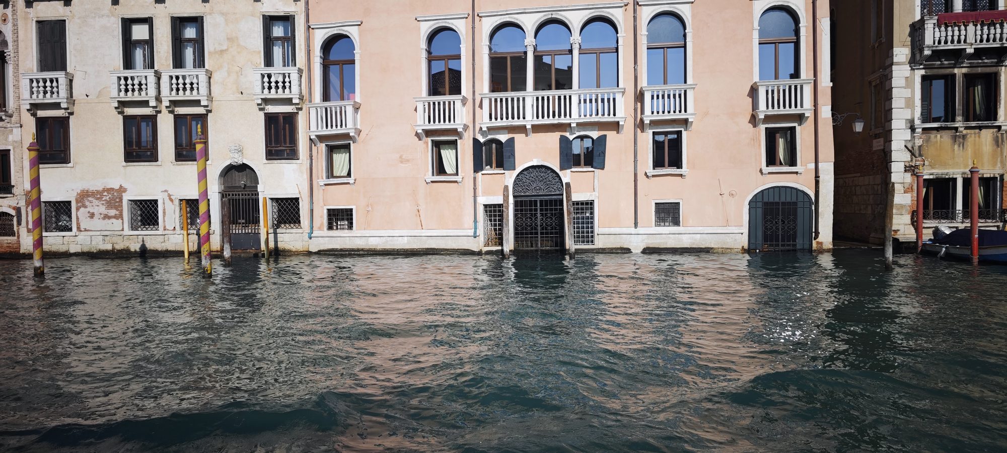 Edificios históricos y postes de amarre sobre las aguas de un canal en Venecia.