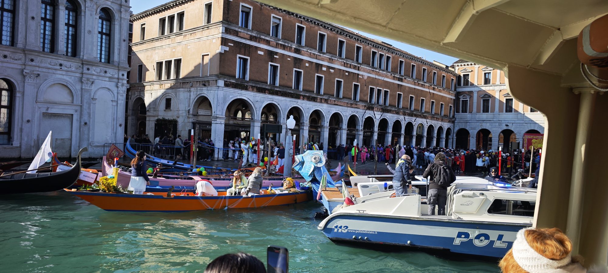 Barcas decoradas y góndolas navegando en el Gran Canal frente a edificios históricos de Venecia.