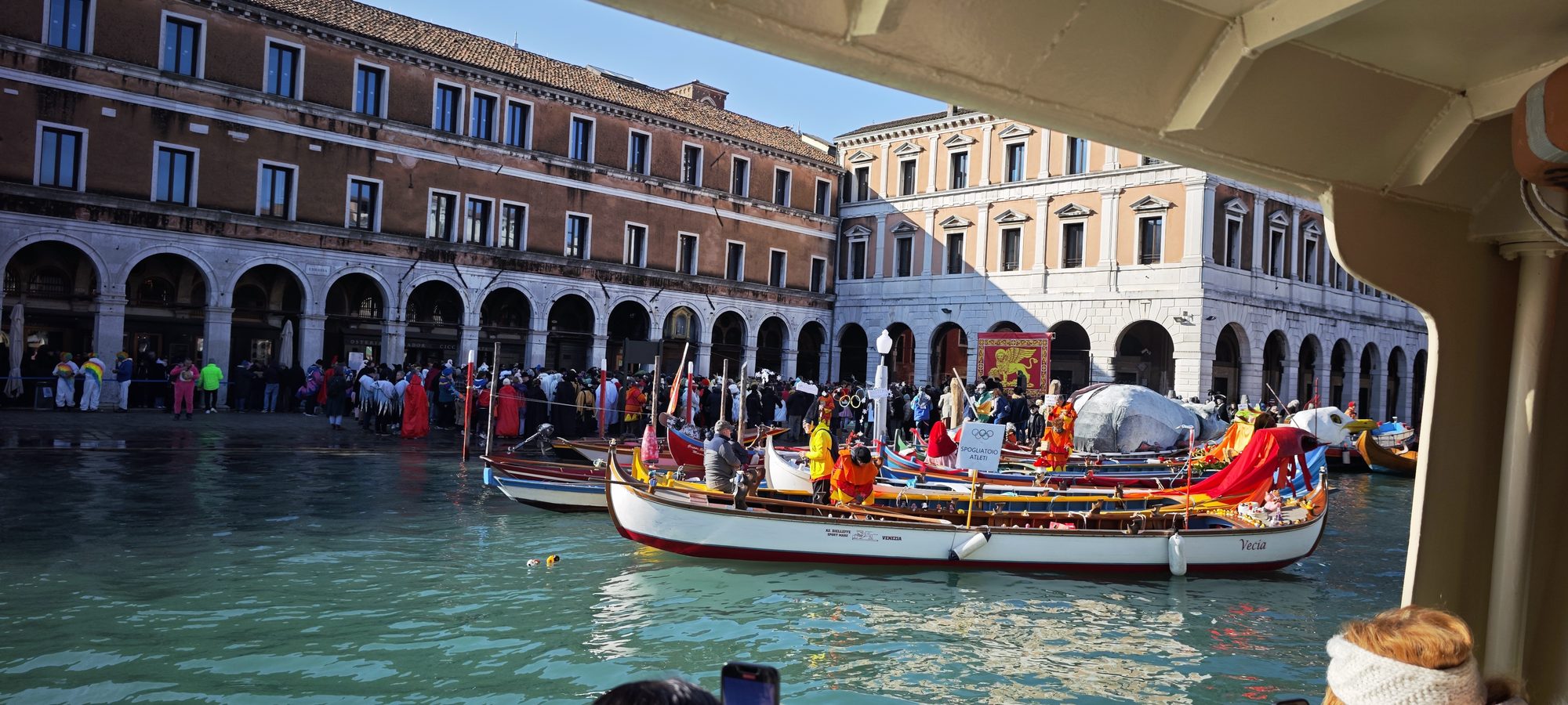 Barcas tradicionales decoradas navegando en un canal de Venecia junto a edificios históricos.