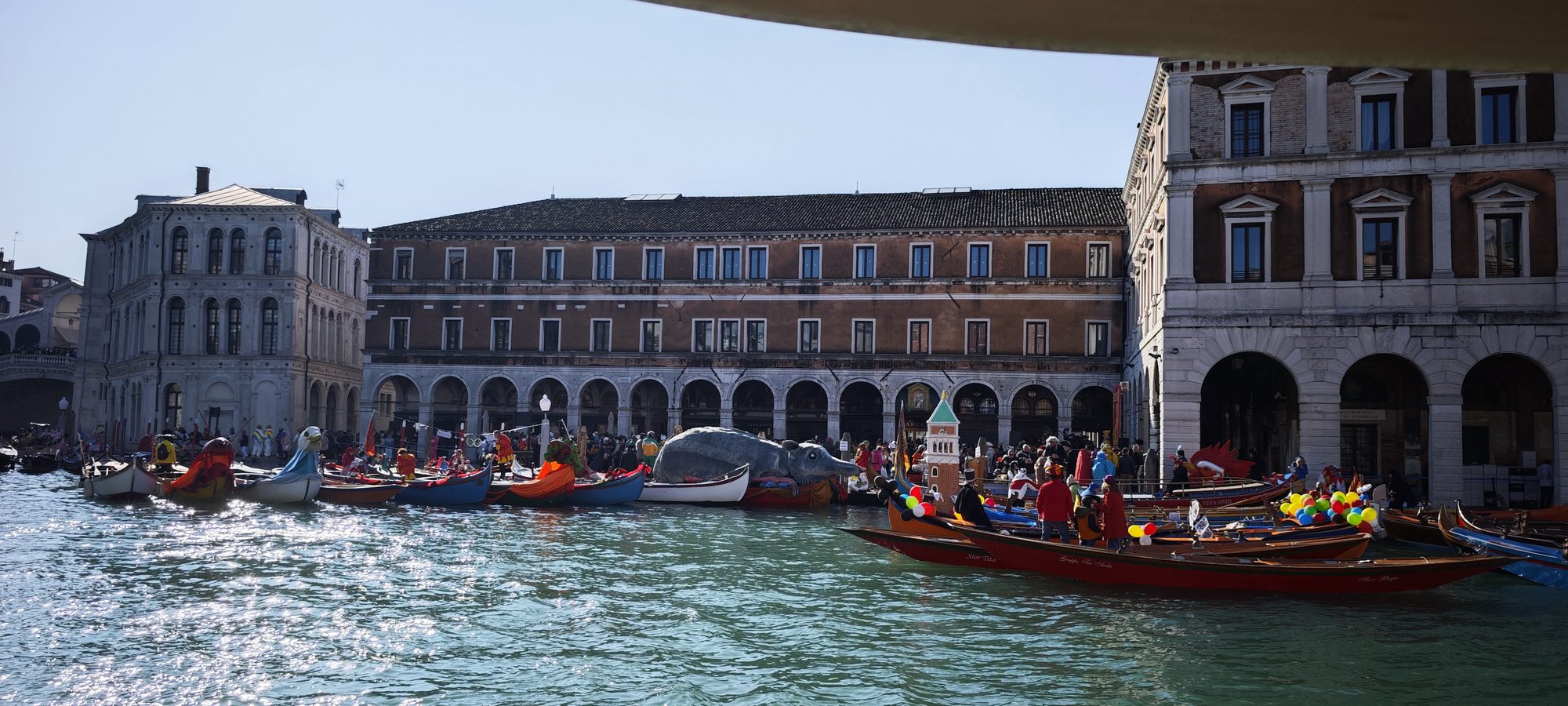 Góndolas y embarcaciones decoradas navegando por el Gran Canal de Venecia entre edificios históricos.