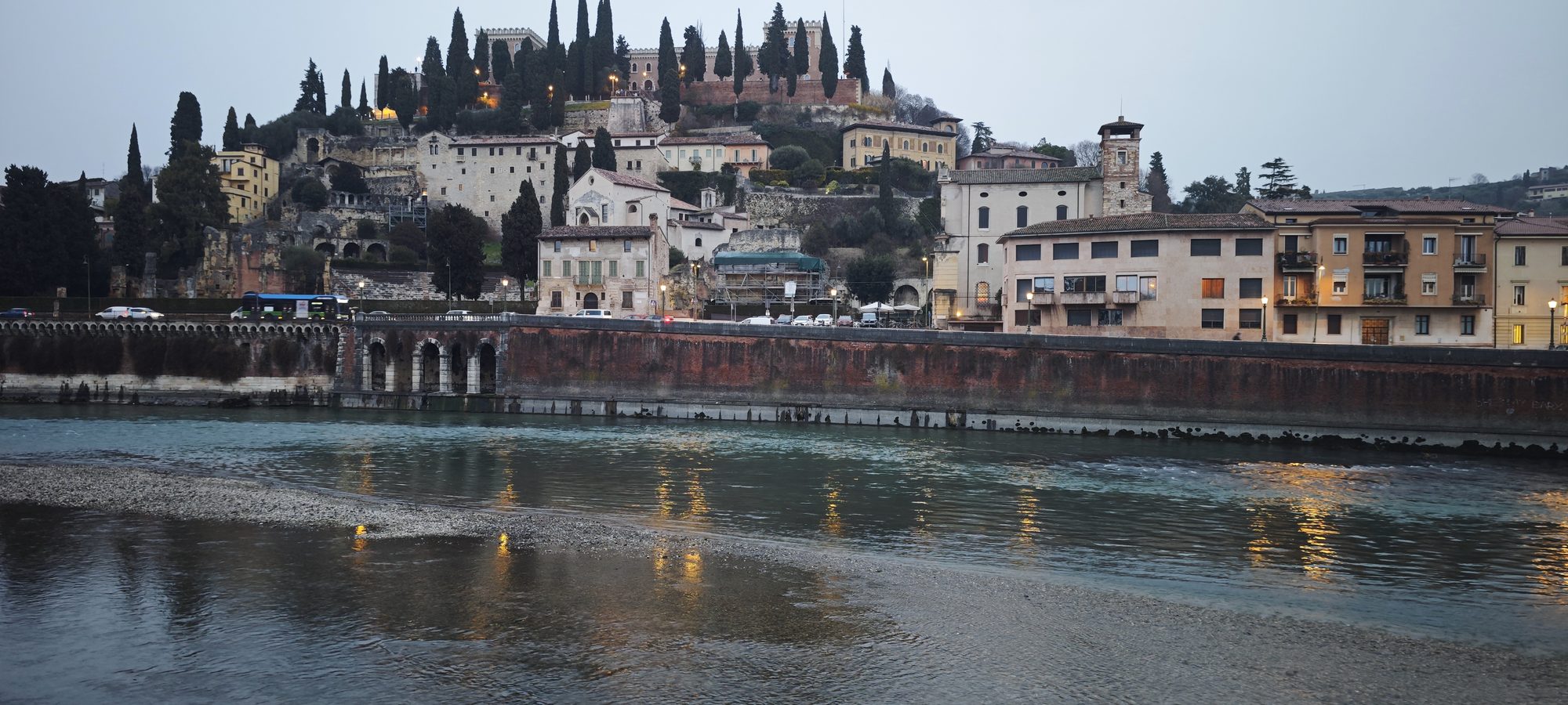Edificios históricos y cipreses en la colina junto al río Adigio en Verona.