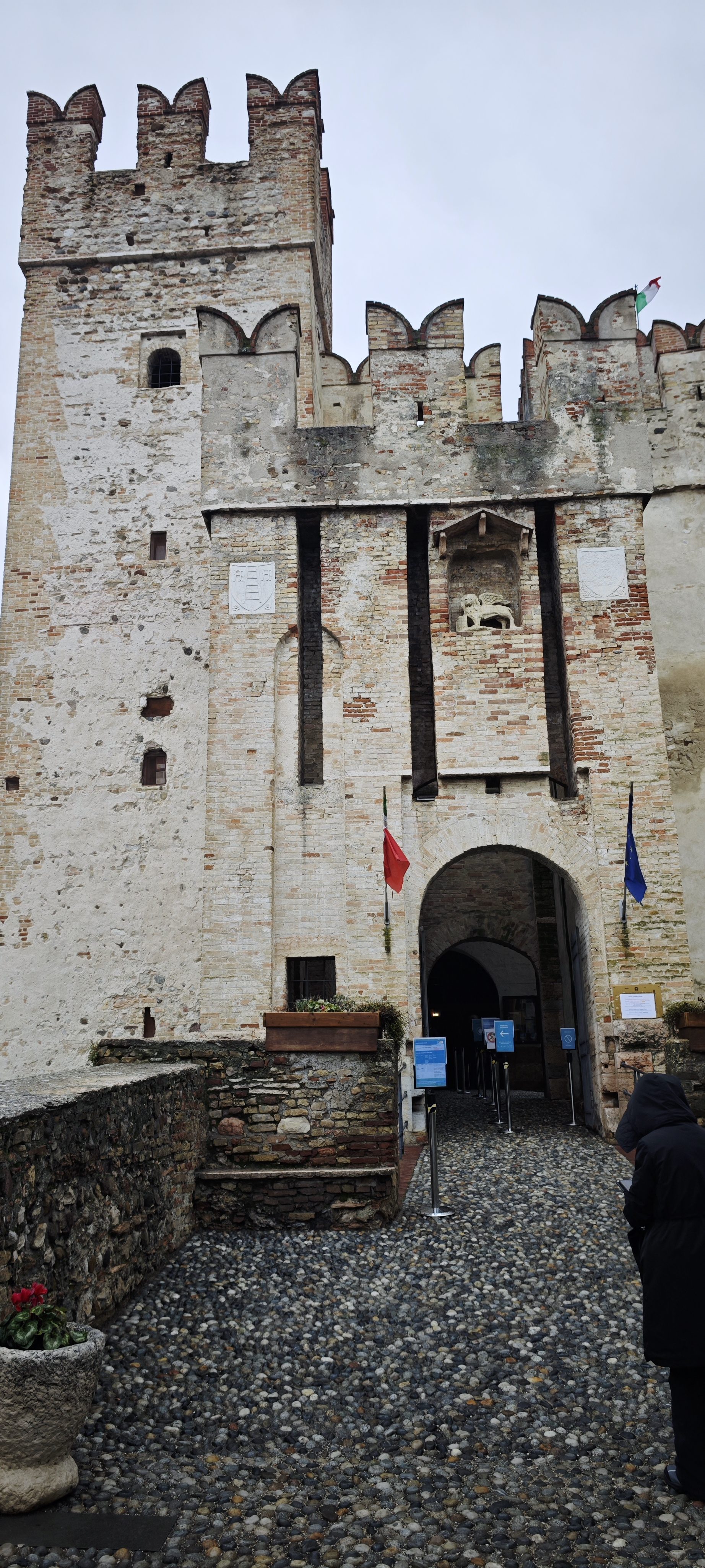 Fachada de piedra y entrada arqueada del Castillo Scaligero con almenas medievales en Sirmione.