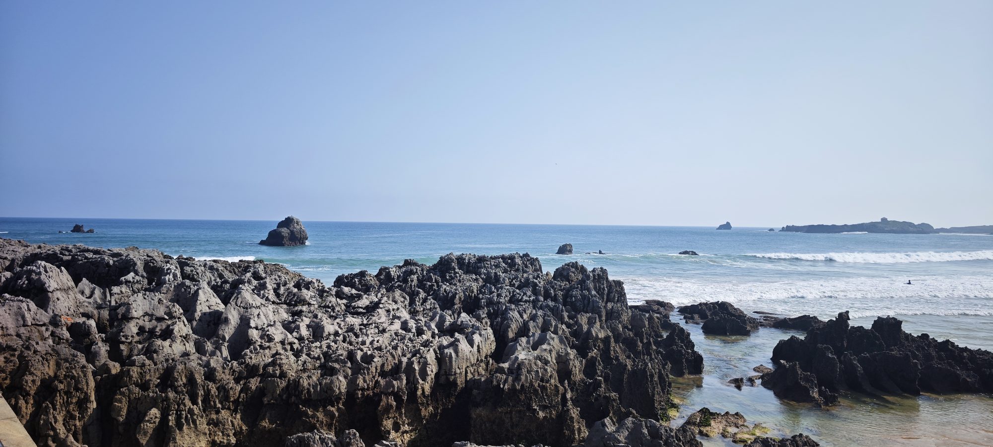 Rocas escarpadas en la costa de Arnuero frente al mar Cantábrico bajo un cielo despejado.