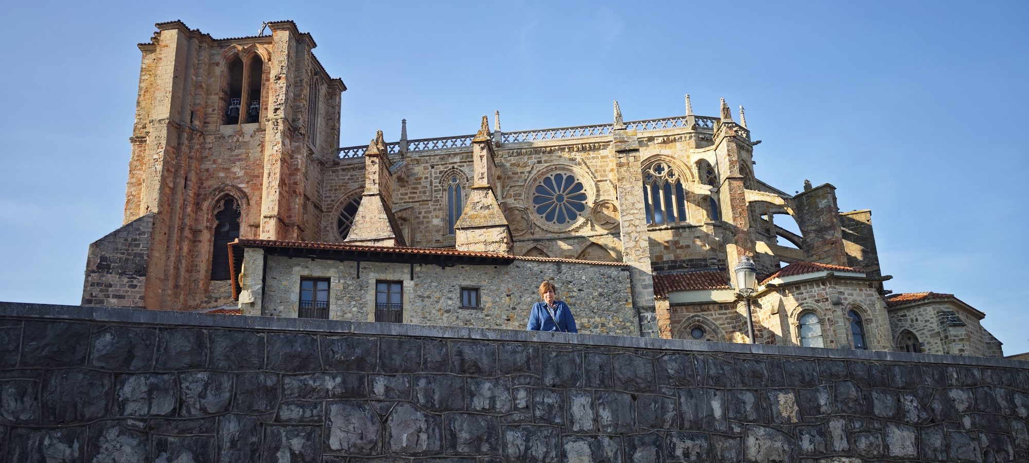 Iglesia gótica de piedra con un gran rosetón y torre bajo un cielo despejado