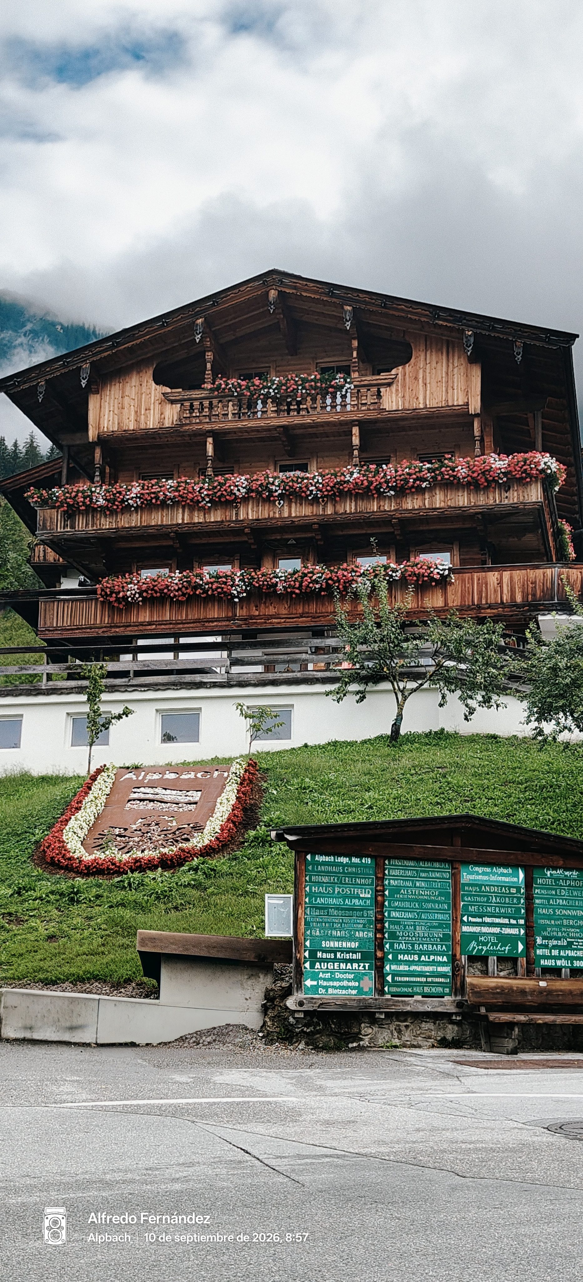 Chalet tradicional de madera con balcones floridos y escudo vegetal en Alpbach, Tirol.