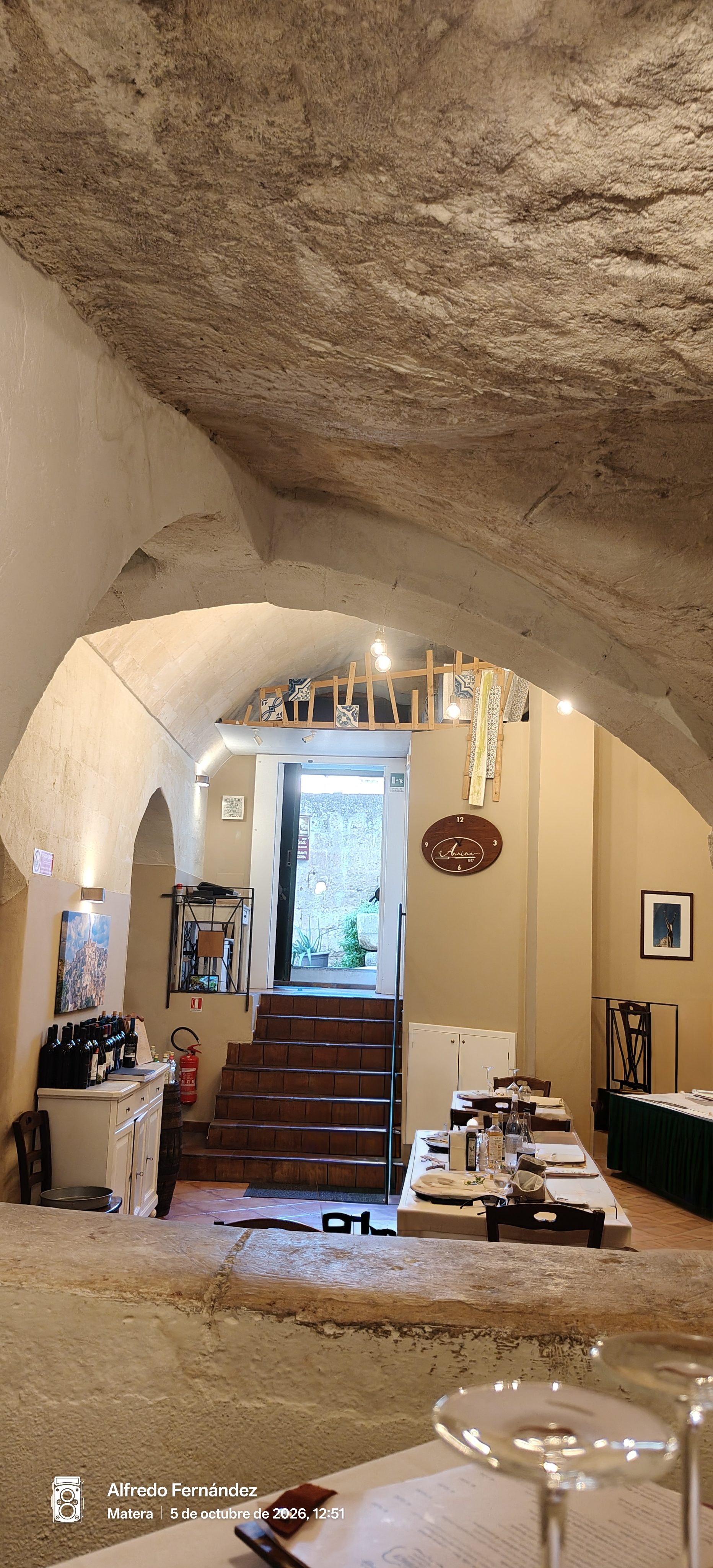Interior de un restaurante rústico excavado en roca con mesas preparadas y arcos tradicionales.
