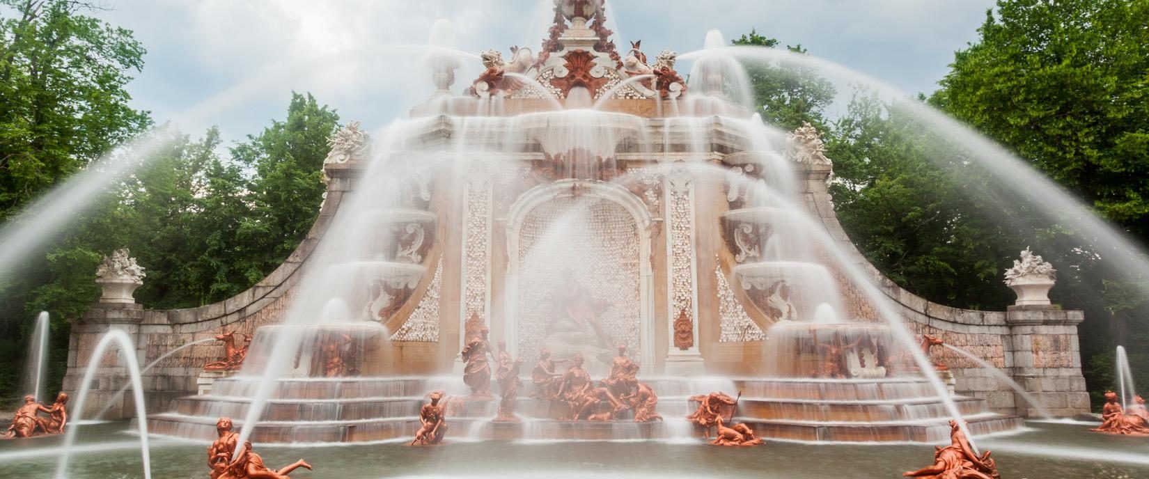 Fuente barroca monumental con esculturas clásicas y potentes chorros de agua en cascada